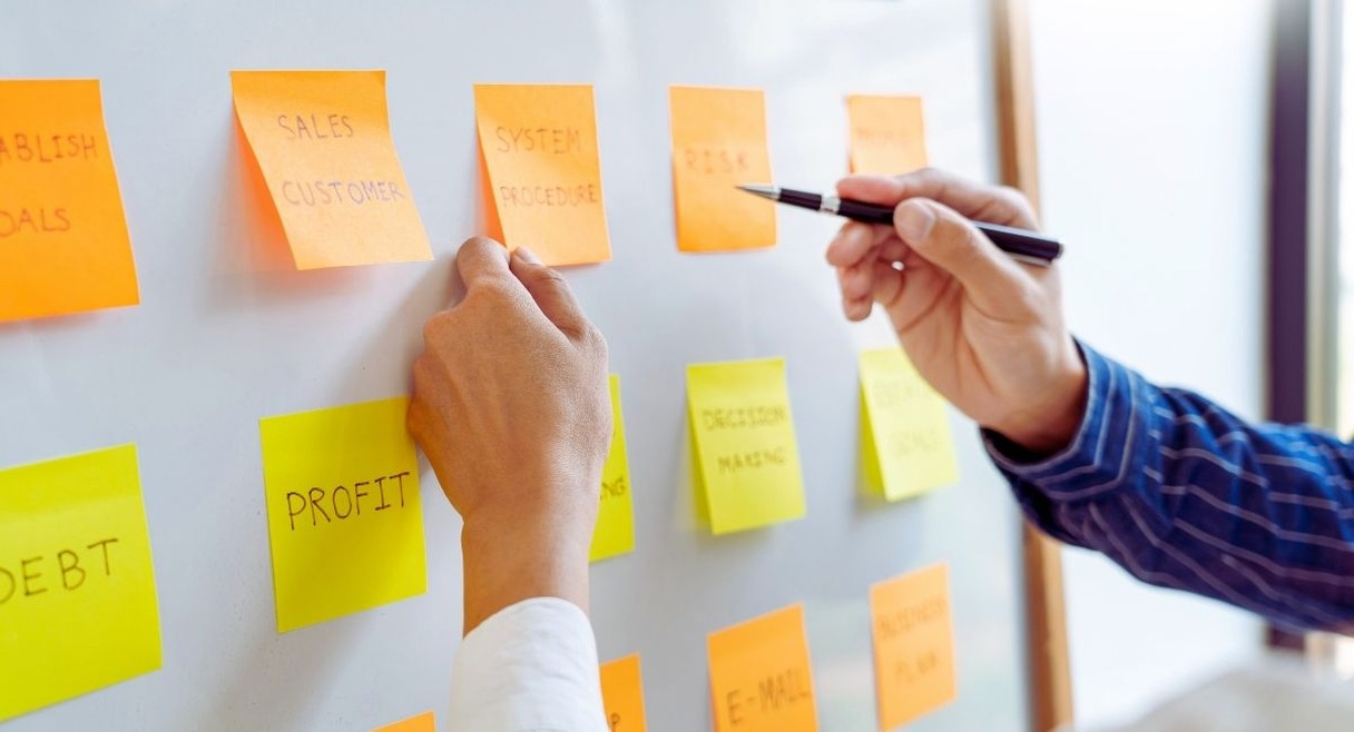 Collegues organisant des notes autocollantes de strategie sur un tableau