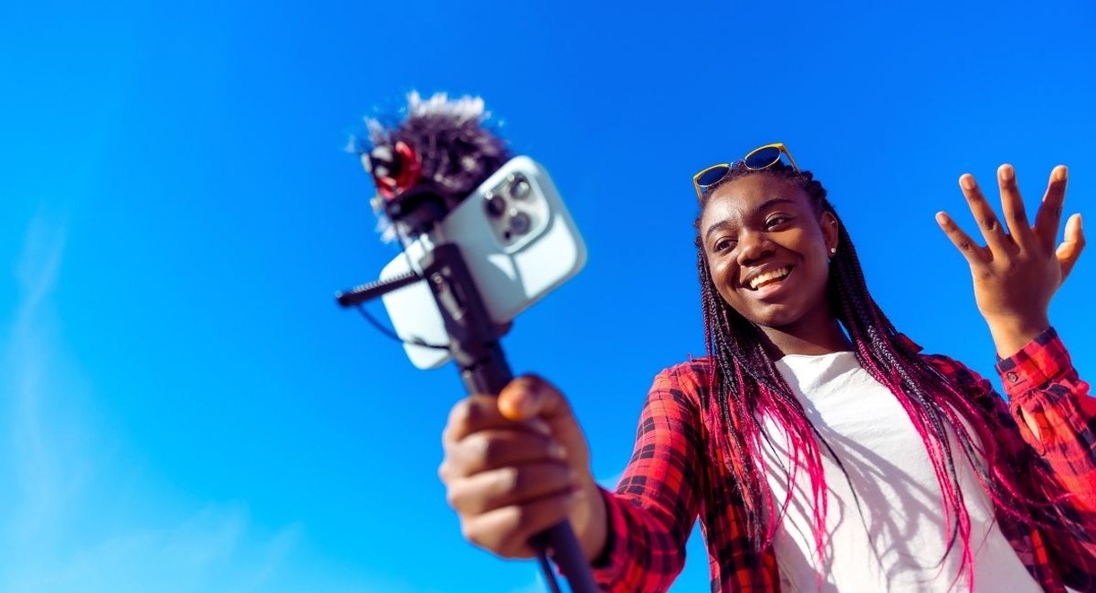 Jeune femme souriante enregistrant une video en exterieur
