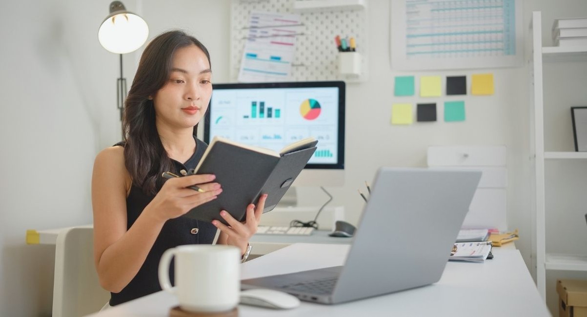 Femme consultant un carnet devant des graphiques marketing