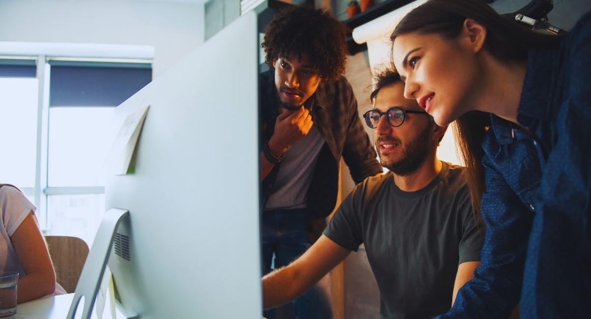 Jeunes collegues regardant un ecran d ordinateur au bureau