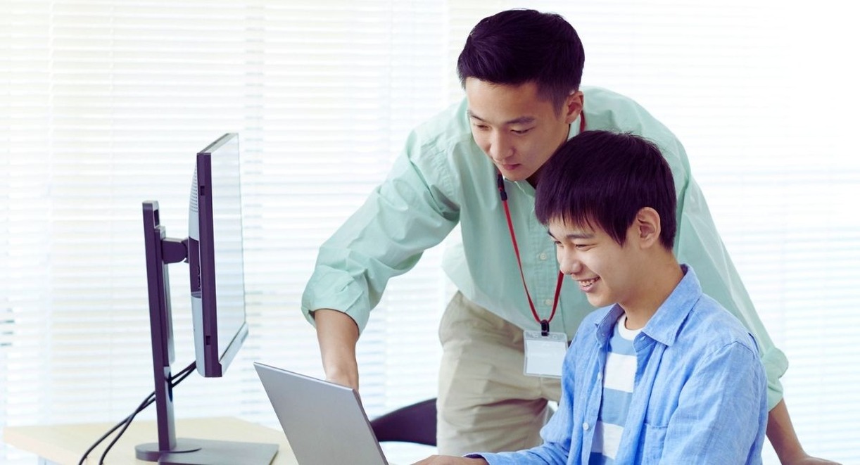 Jeune apprenti et son tuteur devant un ordinateur
