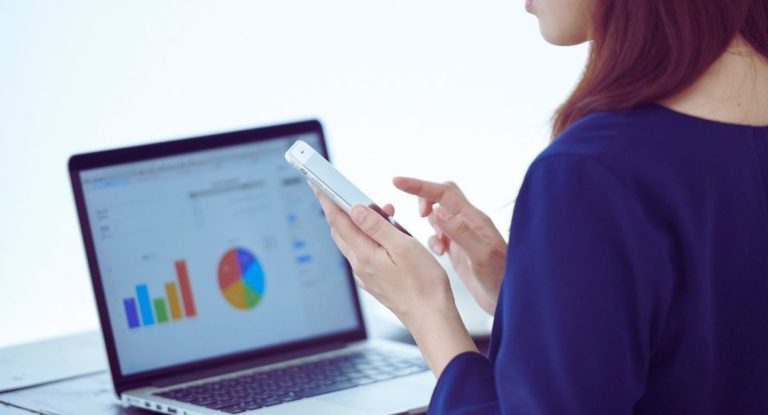 Femme consultant des graphiques de donnees sur un ordinateur portable et un smartphone