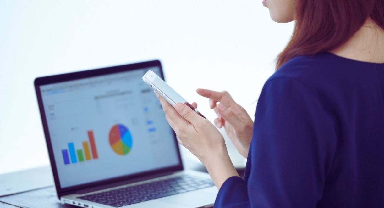 Femme consultant des graphiques de donnees sur un ordinateur portable et un smartphone