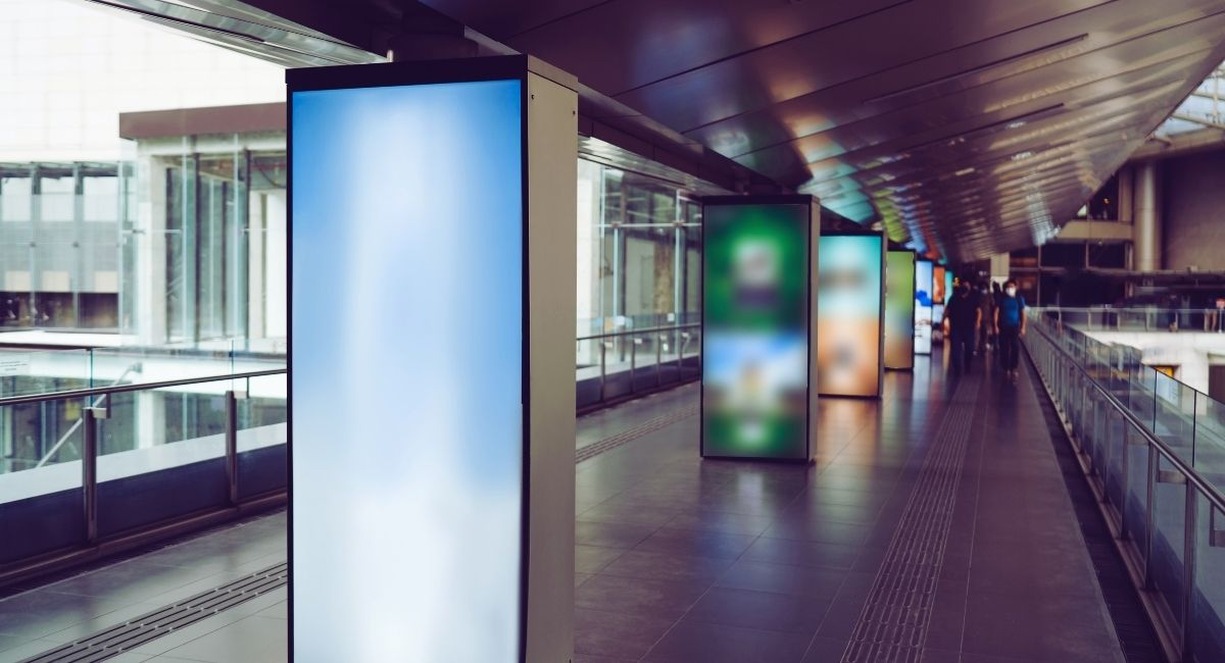 Rangée de totems d'affichage dynamique lumineux le long d'une passerelle piétonne couverte