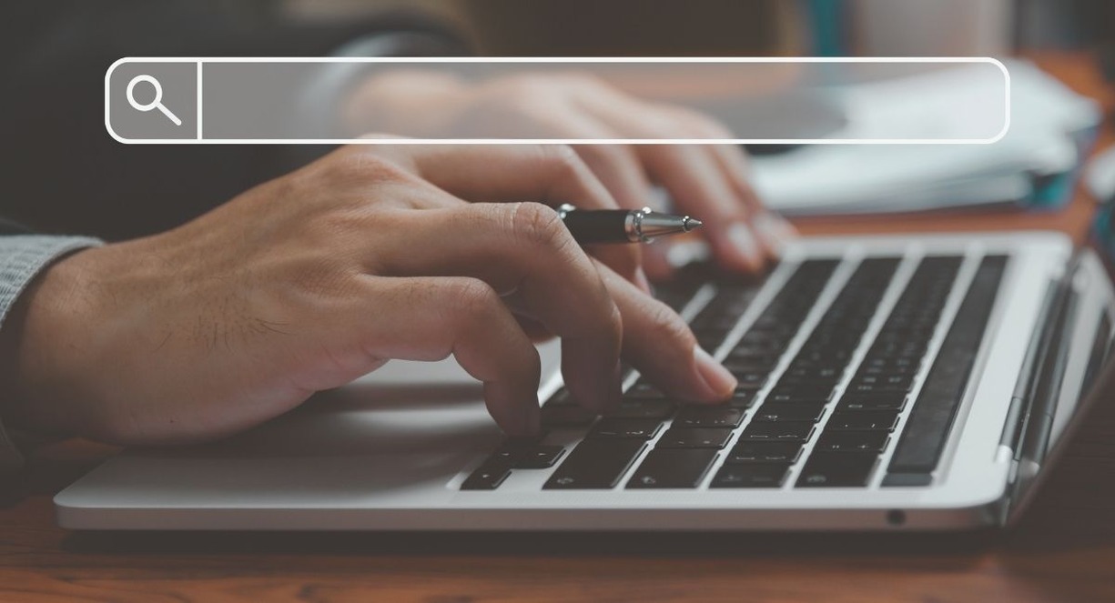 Mains sur le clavier d'un ordinateur portable sous une barre de recherche virtuelle
